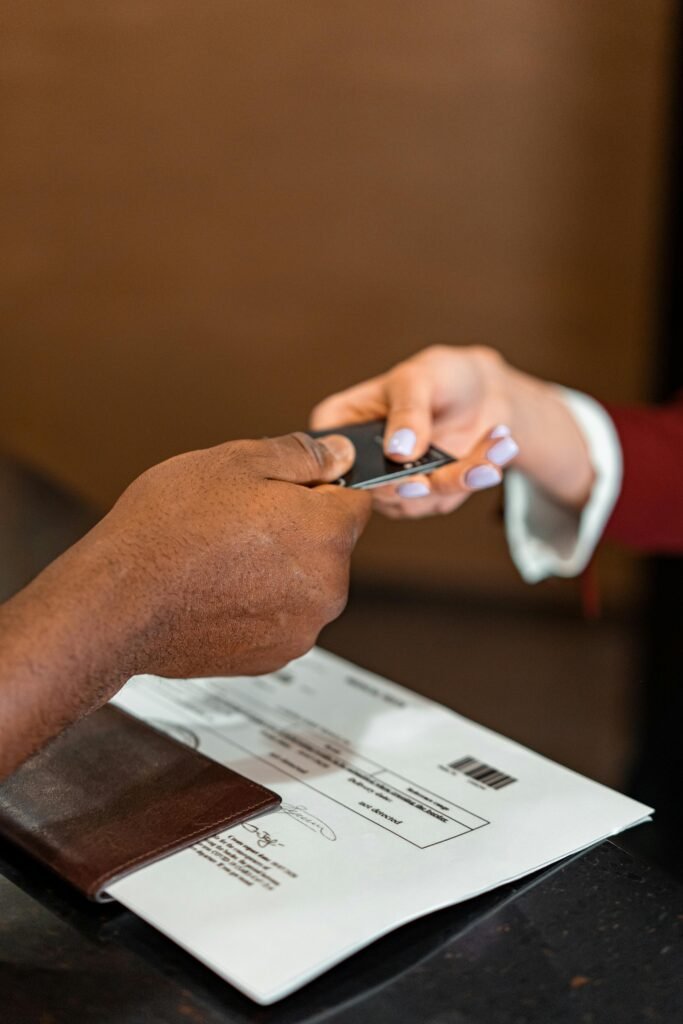 Close-up of hands exchanging a credit card at a counter, highlighting a transaction in progress.